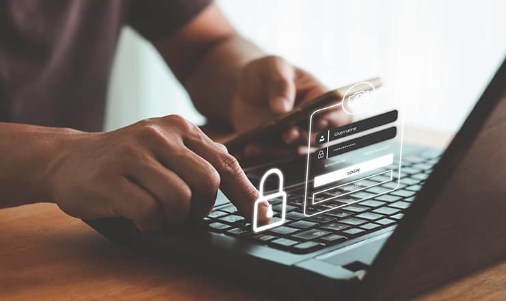 Close up of a man's hands typing on a laptop with a padlock superimposed, indicating two factor authentication