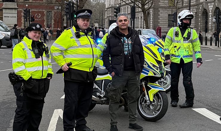 Gas engineer Shoaib Awan, flanked by Metropolitan Police officers and a police motorcycle at a rally at the Houses of Parliament to highlight the problem of tool theft from tradespeople