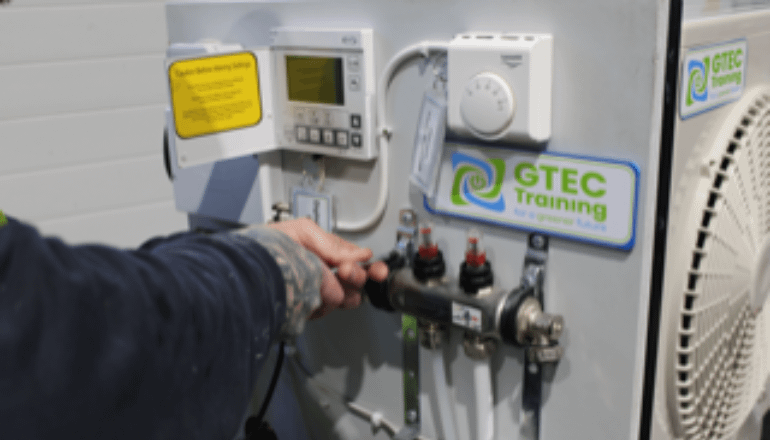 Close up of a man's hands using tools on an air source heat pump